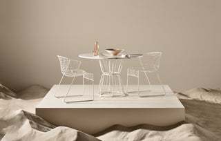Modern wireframe chairs and table on a platform with a neutral background