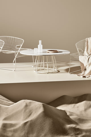 ND lounge chairs and table against a beige wall with sand at the base