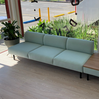 Light blue sofa in a room with large windows showing an outdoor view.