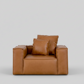 Brown leather armchair with cushions on a light gray background