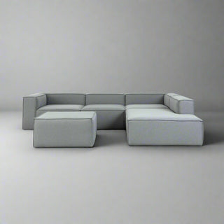 Gray sectional sofa on a concrete floor with a white wall background