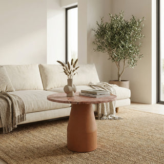 Living room with a beige sofa, round terracotta table, and potted plant.