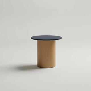 Small round table with black top and beige base on a light gray background