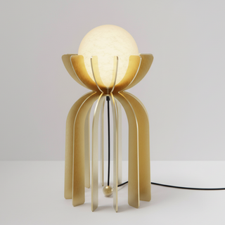 Gold table lamp with a white bulb on a light gray background
