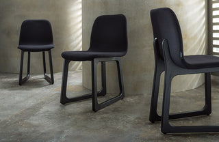Three black chairs arranged in a row against a neutral wall.