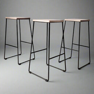 Three bar stools with black metal legs and wooden seats on a grey background