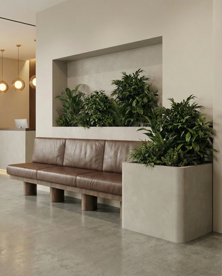 Modern interior with a brown leather bench and large planters filled with greenery.