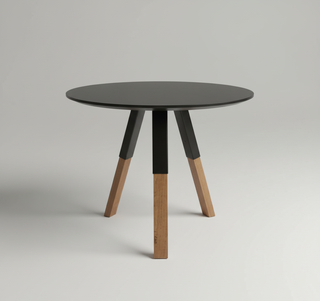 Round table with black top and wooden legs on a gray background