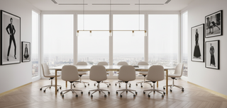 Modern conference room with a large table and chairs, large windows, and framed pictures on the wall.